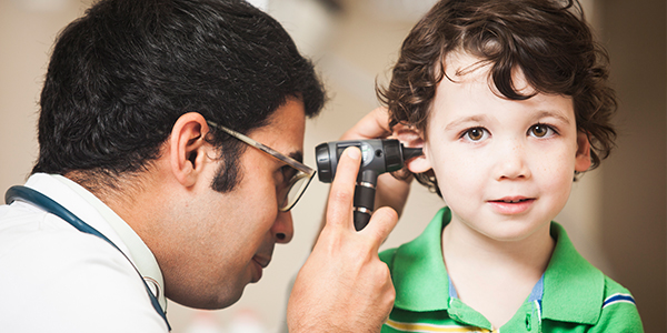 Male doctor examining little boy's ear