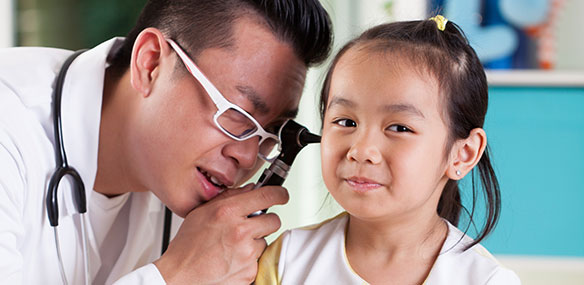Pediatrician examining girl's ear