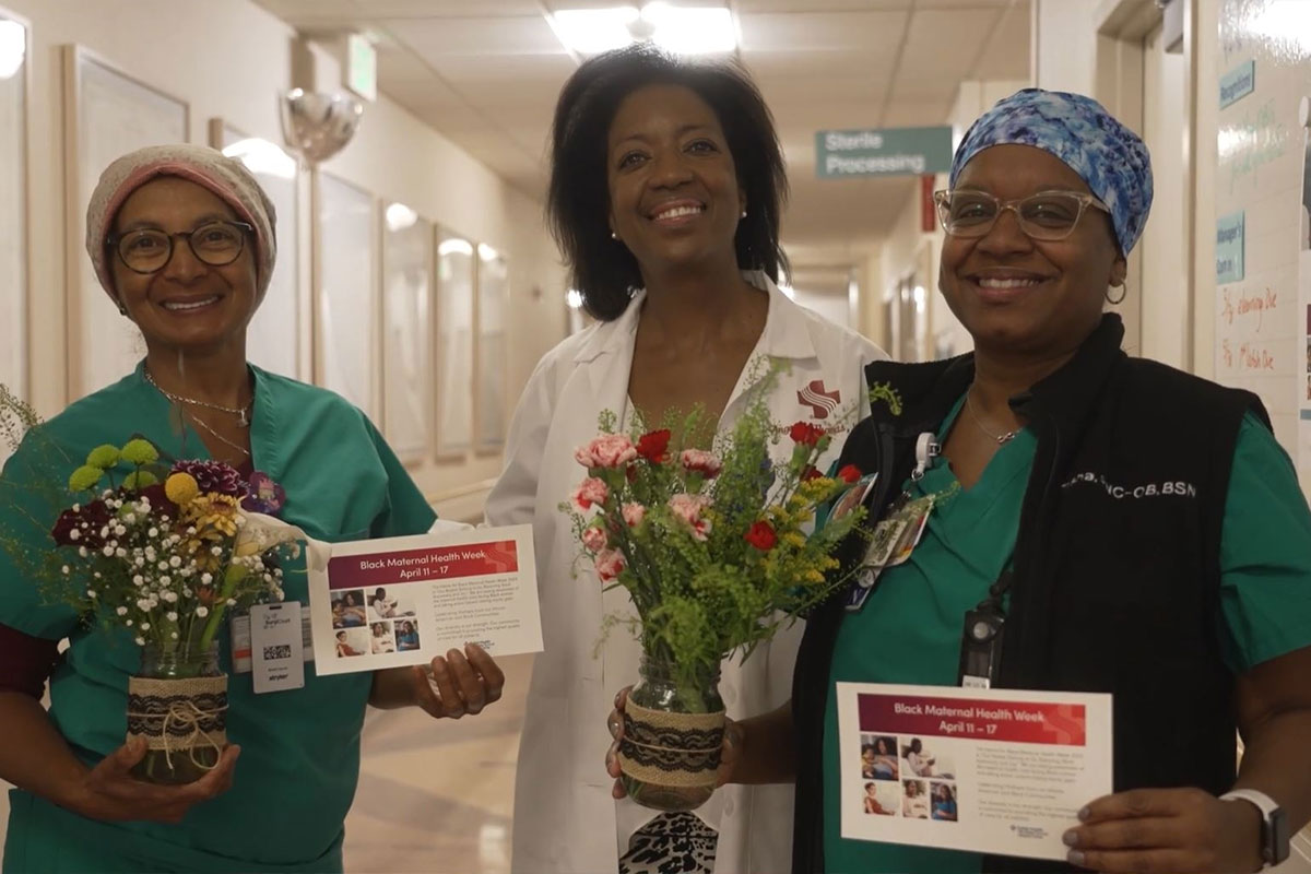 Three female medical professionals with flowers and cards.