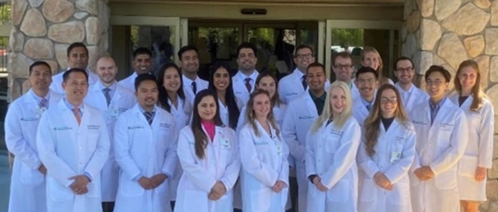 A group of doctors smiling and posing for a photo outside a medical facility.